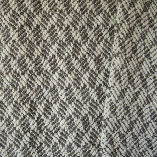 Detail of gray and white braided blocks wool blanket.