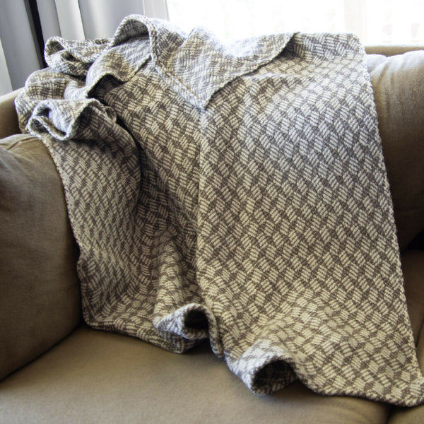 Braided blocks wool blanket draped over couch.