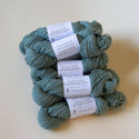 Skeins of blue-green yarn in a stack.